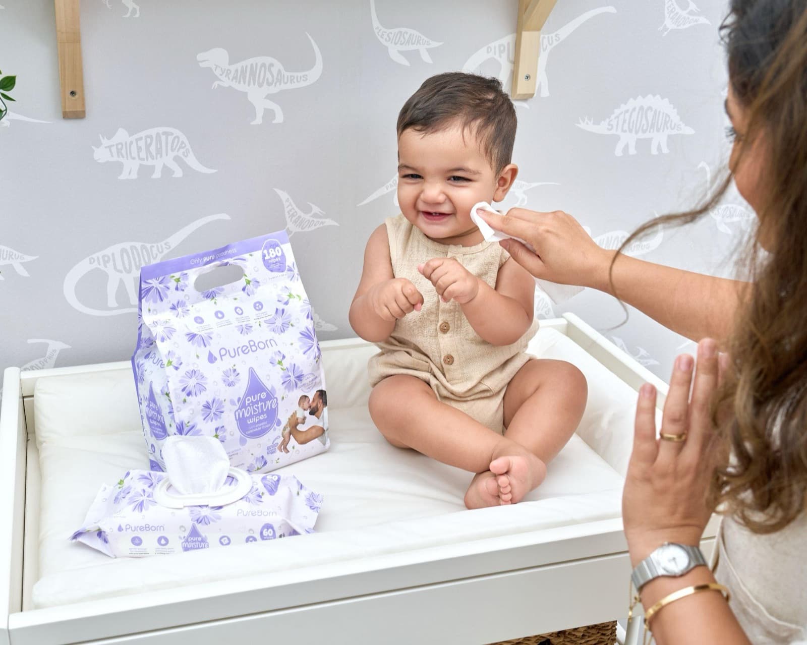 Mum wiping her smiling baby's face with Pure Moisture Wipes